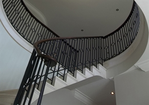 'The staircase, railed with delicately wrought iron, rose in a gracious curve to a railed gallery.'